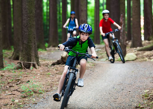 Two young kids ride their mountain bikes down a track